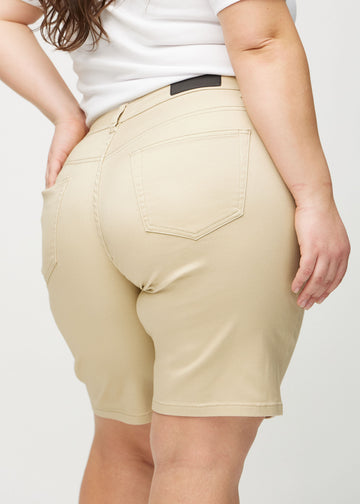 Beige regular middle shorts sett bakfra på nært hold på en plus-size-modell for å vise detaljer.