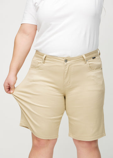 Plus-size-modellen strekker shortsen ved låret for å vise stretch.