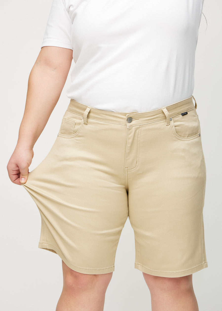Plus-size-modellen strekker shortsen ved låret for å vise stretch.