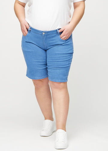 Blå regular middle shorts, modellnavn Geraniums, som går rett ned langs benet og slutter rett over kneet på en plus-size modell, sett forfra.