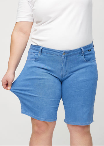 Plus-size modell strekker shortsene ved låret for å vise stretch.