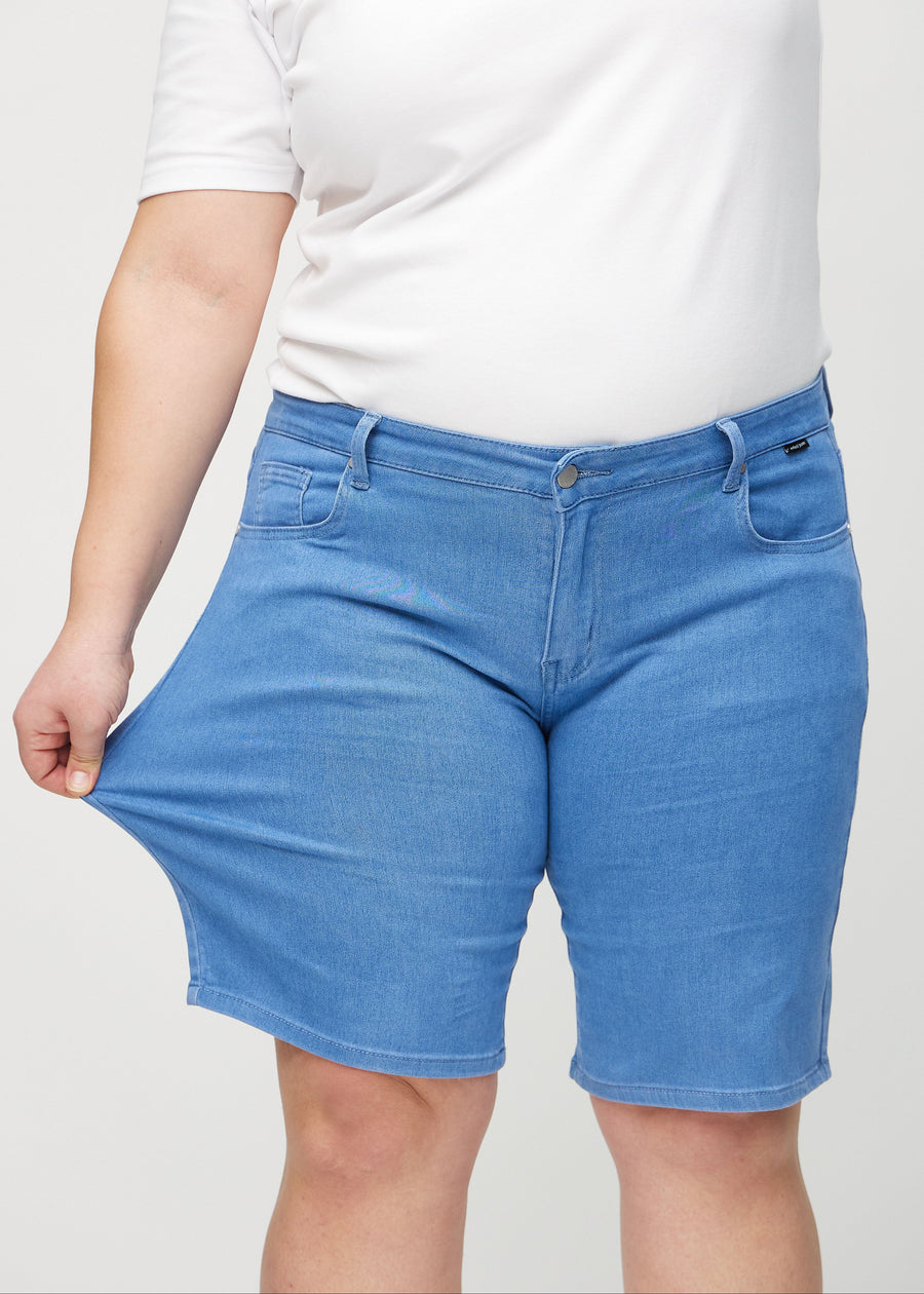 Plus-size modell strekker shortsene ved låret for å vise stretch.