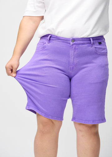 Plus-size-modell strekker shortsen ved låret for å vise stretch.