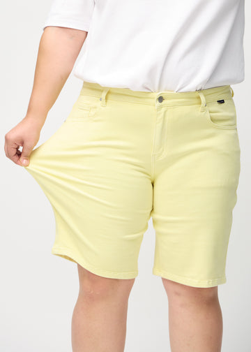 Plus-size-modellen strekker shortsen ved låret for å vise stretch.