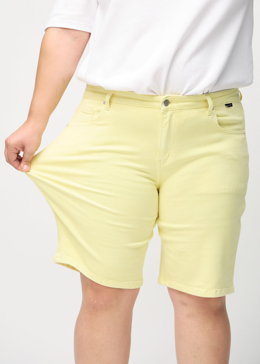 Plus-size-modellen strekker shortsen ved låret for å vise stretch.