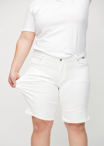 Plus-size modell strekker shortsene ved låret for å vise stretch.