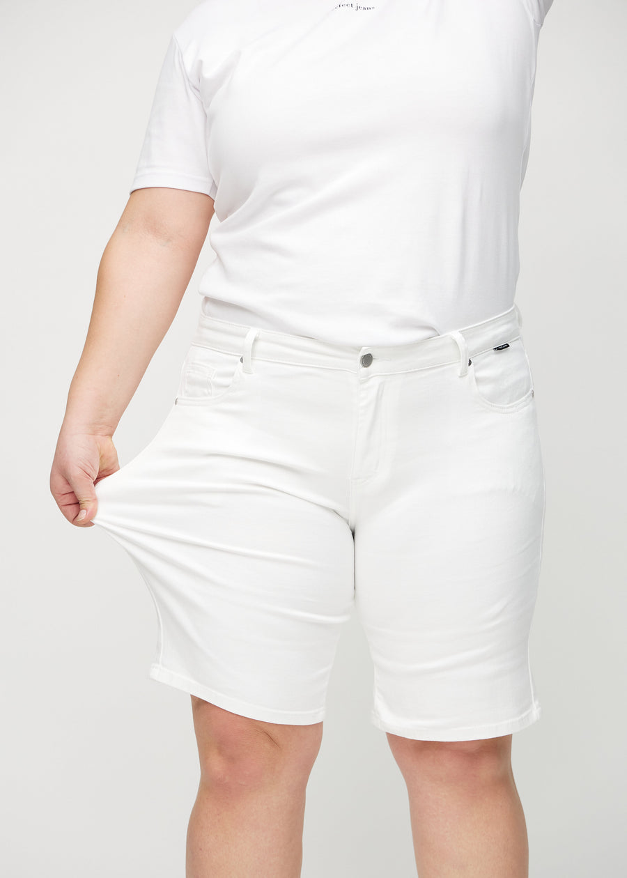 Plus-size modell strekker shortsene ved låret for å vise stretch.
