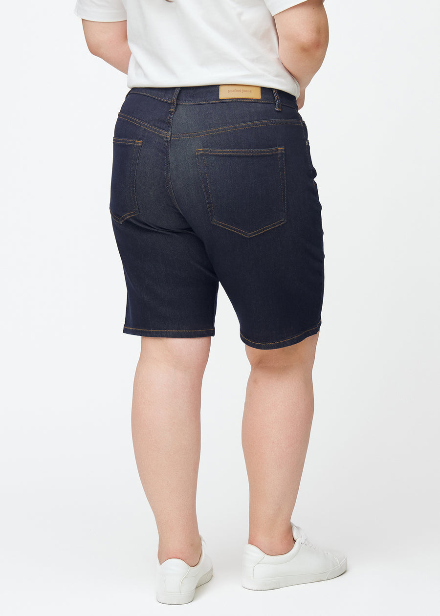 Dyp mørkeblå denimshorts til dame i fargen Midnights sett bakfra på plus-size modell.