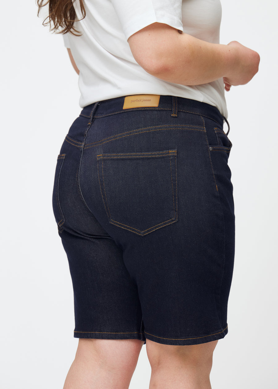 Dyp mørkeblå denimshorts til dame i fargen Midnights sett bakfra i nærbilde på plus-size modell.