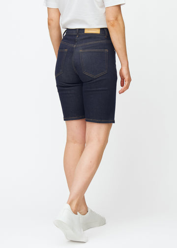 Dyp mørkeblå denimshorts til dame i fargen Midnights sett bakfra, slik at lengden rett over kneet vises.