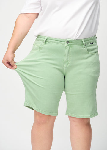 Plus-size modell strekker shortsen ved låret for å vise stretch.