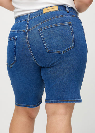 Mørk denim regular middle shorts sett bakfra på nært hold på en plus-size modell for å vise detaljer.