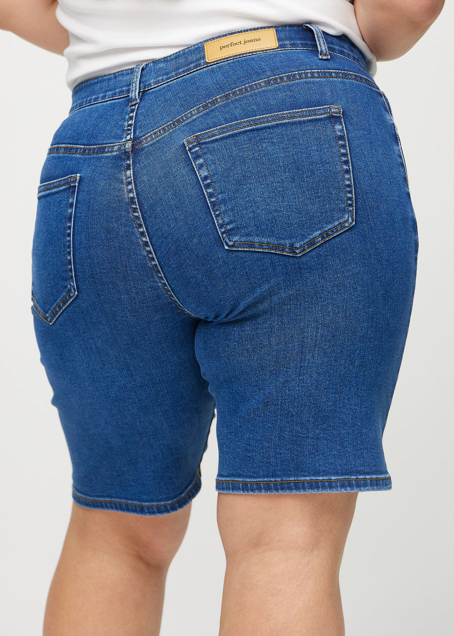Mørk denim regular middle shorts sett bakfra på nært hold på en plus-size modell for å vise detaljer.