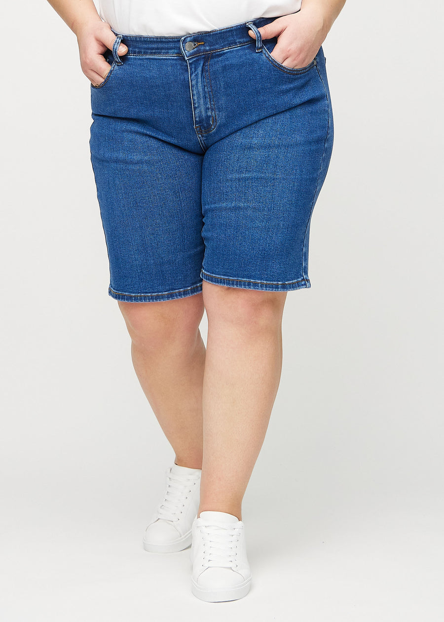 Mørk denim regular middle shorts, modellnavn Oceans, som går rett ned langs benet og slutter rett over kneet på en plus-size modell, sett forfra.