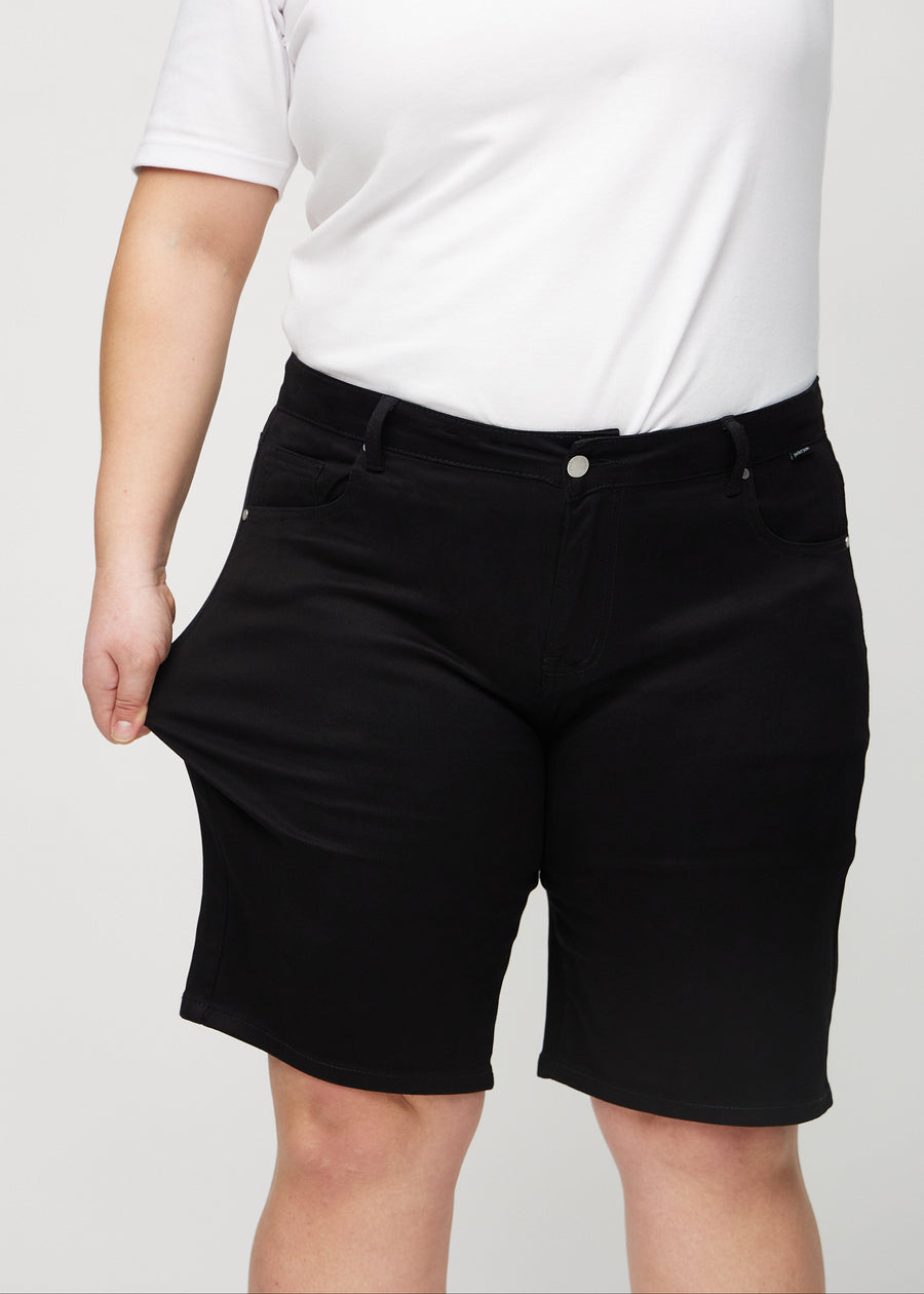 Plus-size modellen strekker shortsen ved låret for å vise stretch.