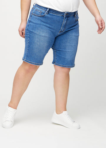 Denim regular middle shorts, modellnavn Rivers, som går rett ned langs benet og slutter rett over kneet på en plus-size-modell, sett forfra.
