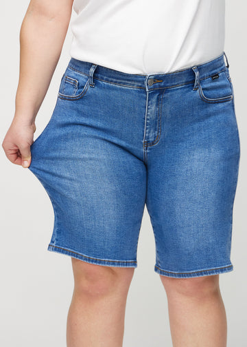 Plus-size-modellen strekker shortsen ved låret for å vise stretch.