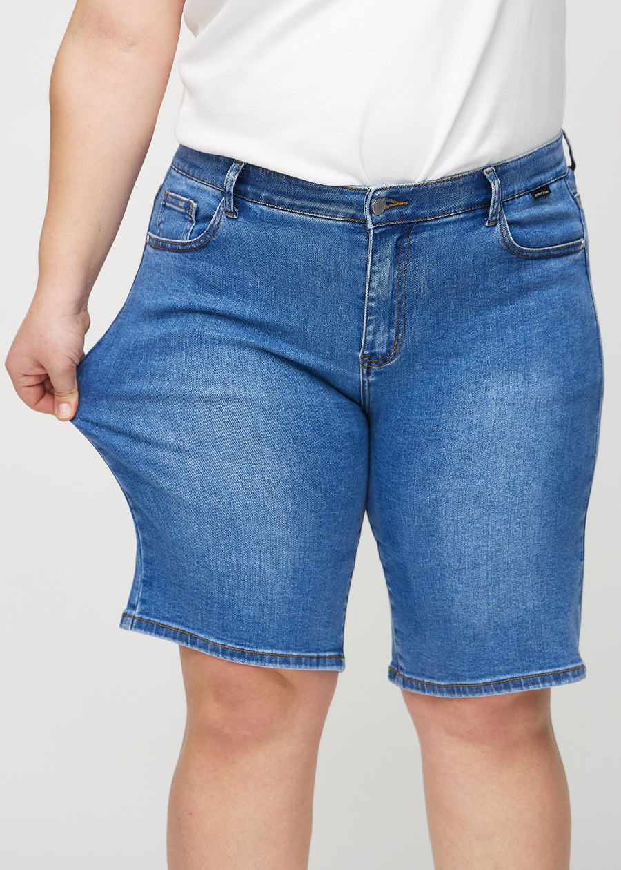 Plus-size-modellen strekker shortsen ved låret for å vise stretch.