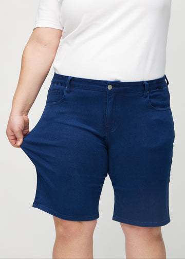 Plus-size modellen strekker shortsene ved låret for å vise stretch.