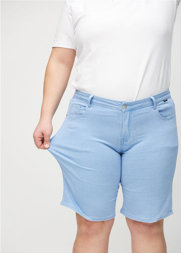 Plus-size-modellen strekker shortsen ved låret for å vise stretch.