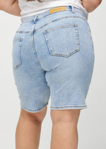 Lys denim regular middle shorts sett bakfra på nært hold på en plus-size modell for å vise detaljer.