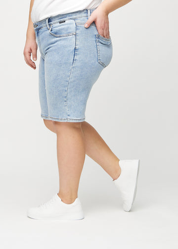Lys denim regular middle shorts sett fra siden på en plus-size modell.