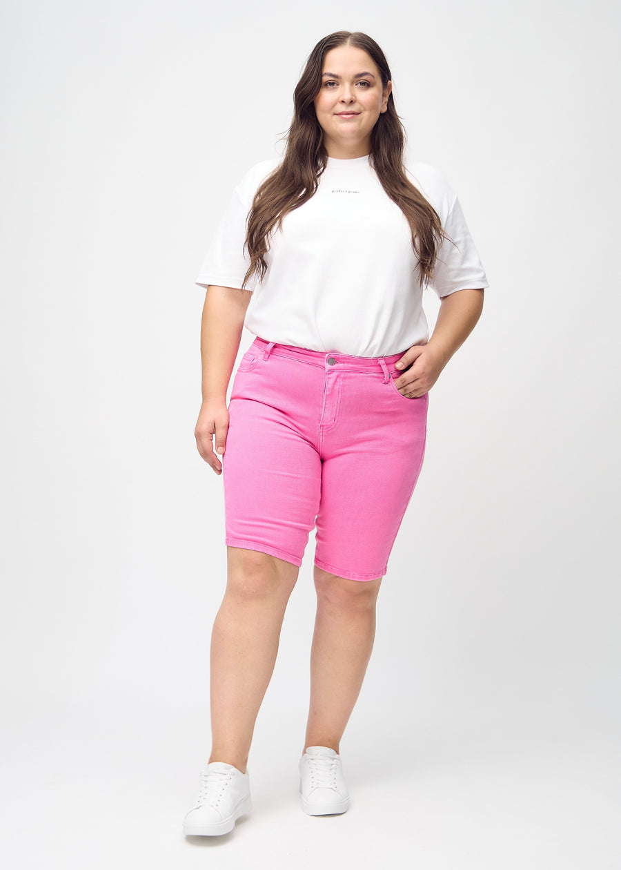 Fullt bilde av en plus-size modell i lyserosa skinny middle shorts.