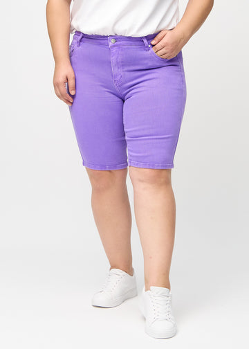 Lilla skinny middle shorts, modellnavn Lavenders, som sitter tett på låret og slutter rett over kneet på en plus-size-modell, sett forfra.