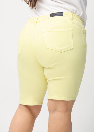 Lysegule skinny middle shorts sett bakfra på nært hold på en plus-size-modell for å vise detaljer.