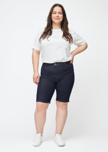 Helbilde av plus-size modell i dyp mørkeblå denimshorts til dame i fargen Midnights med skinny passform.