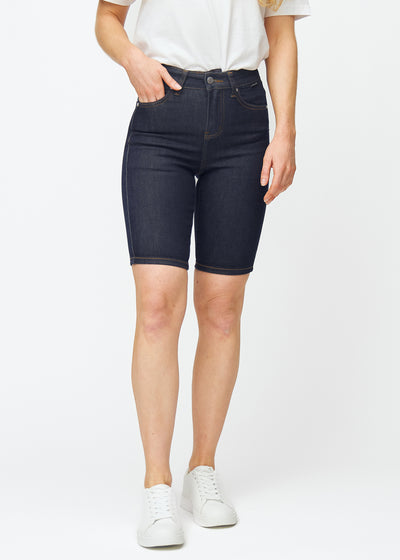Dyp mørkeblå denimshorts til dame i fargen Midnights med skinny passform som sitter tett ved hoften og følger lårene, sett forfra.