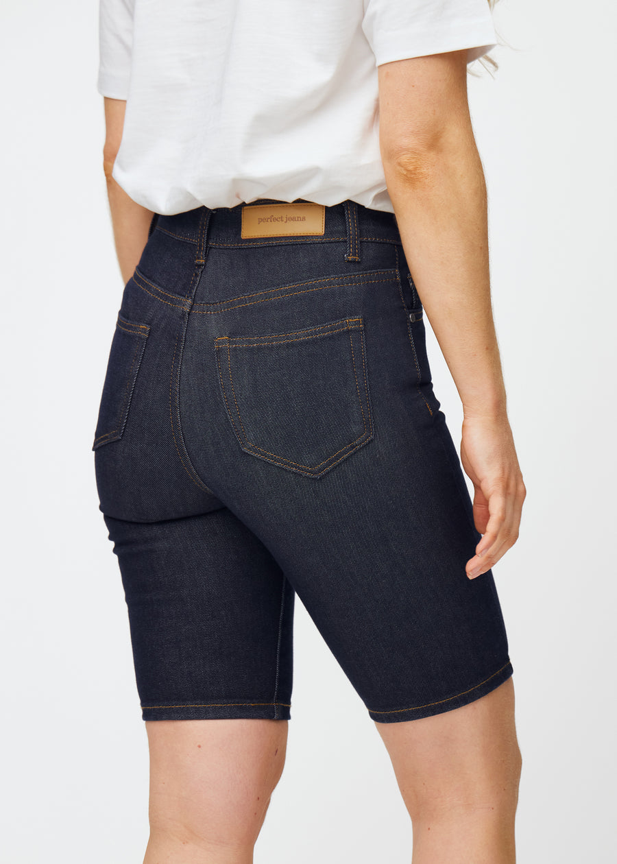 Dyp mørkeblå denimshorts til dame i fargen Midnights sett bakfra i nærbilde for å vise passform og detaljer.