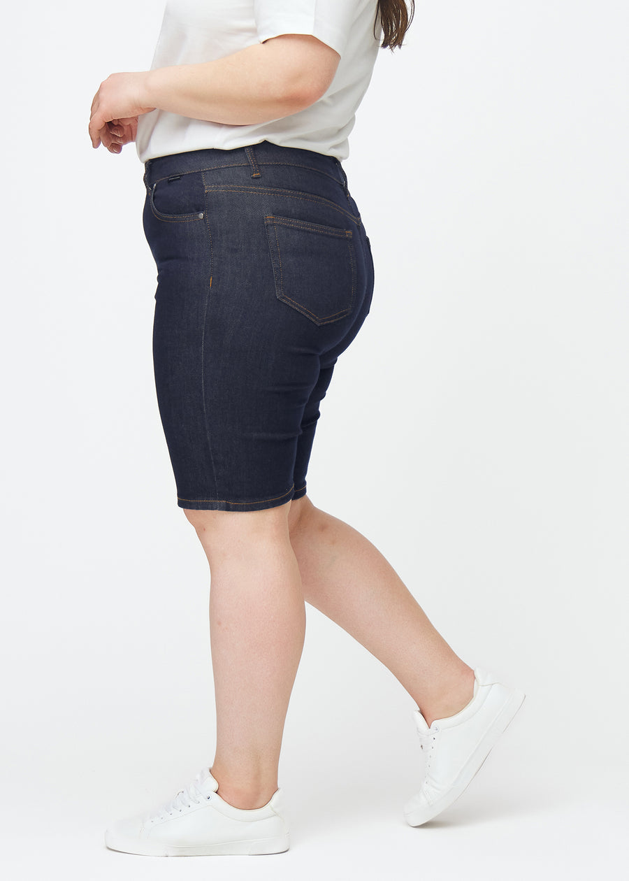 Dyp mørkeblå denimshorts til dame i fargen Midnights med skinny passform sett fra siden på plus-size modell.