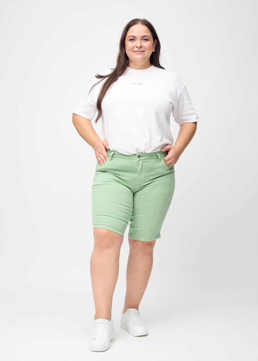 Fullt bilde av en plus-size-modell i lysegrønne skinny middle shorts.