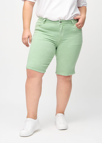 Lysegrønne skinny middle shorts, modellnavn Mints, som sitter tett på låret og slutter rett over kneet på en plus-size-modell, sett forfra.