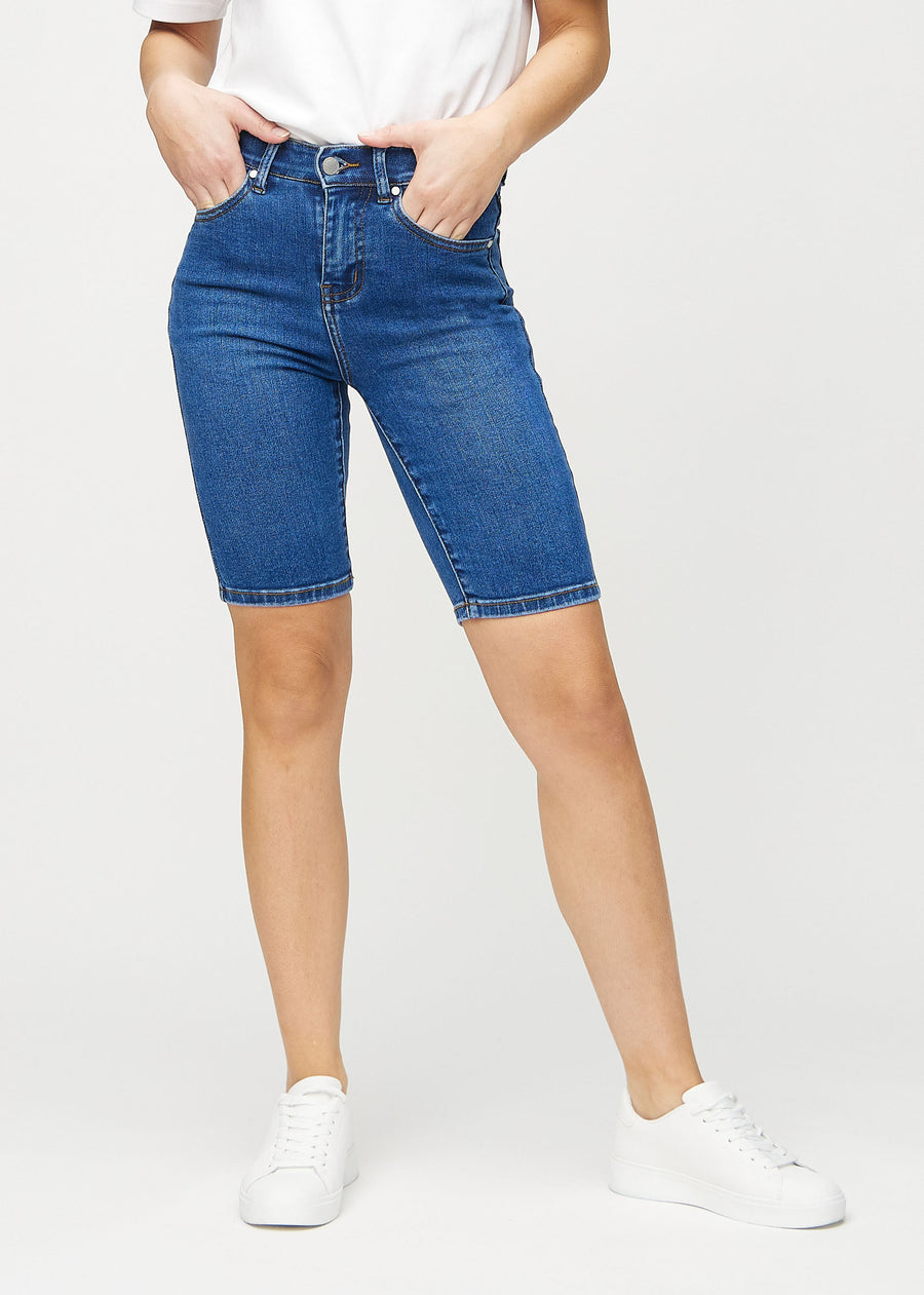 Mørk denim skinny middle shorts, modellnavn Oceans, som sitter tett på låret og slutter rett over kneet, sett forfra.