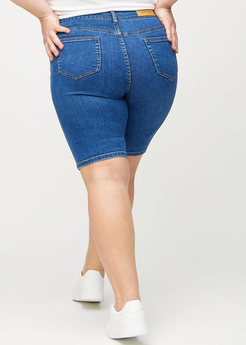 Mørk denim skinny middle shorts sett bakfra på en plus-size modell, så man kan se hele produktet.