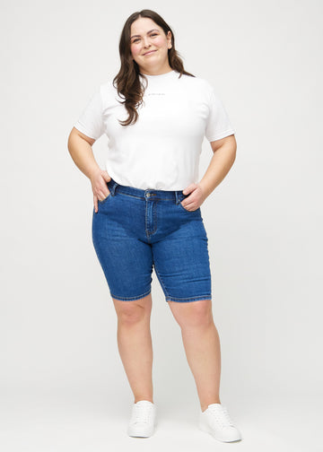 Fullt bilde av en plus-size modell i mørk denim skinny middle shorts.