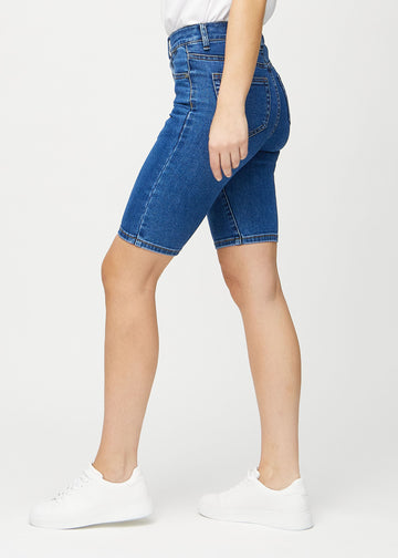 Mørk denim skinny middle shorts sett fra siden på modell.