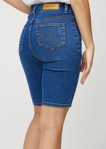 Mørk denim skinny middle shorts sett bakfra på nært hold for å vise detaljer.