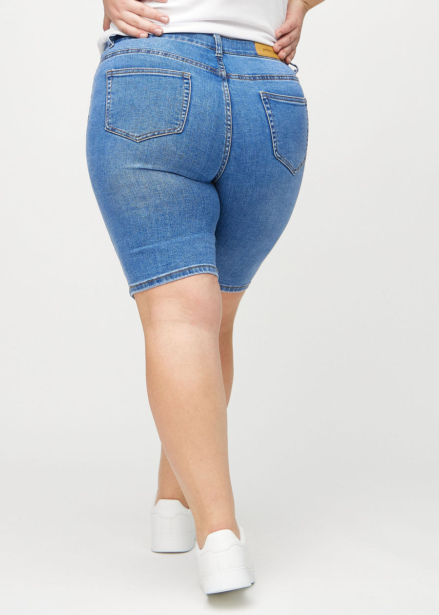 Denim skinny middle shorts sett bakfra på en plus-size-modell, slik at man kan se hele produktet.