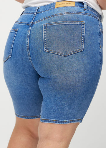 Denim skinny middle shorts sett bakfra på nært hold på en plus-size-modell for å vise detaljer.