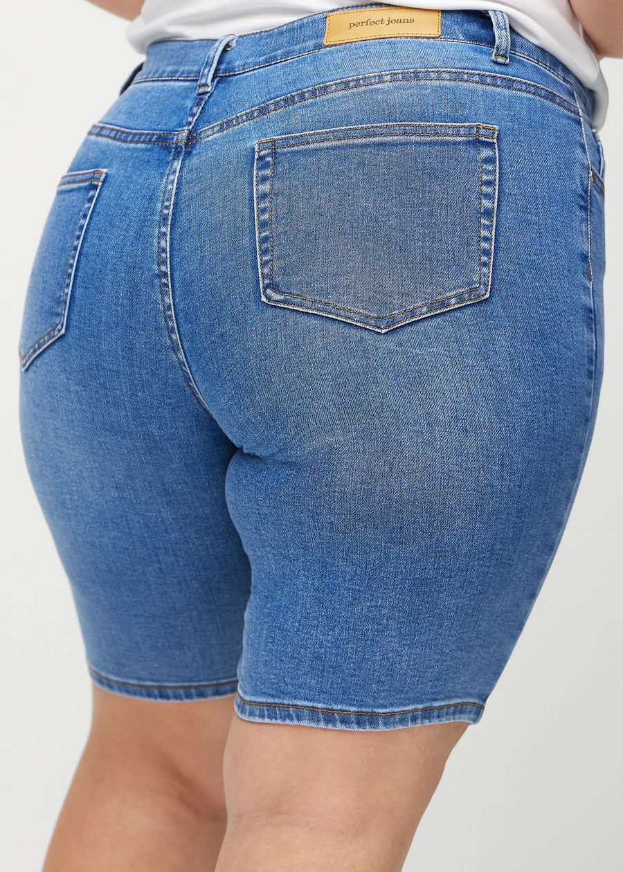 Denim skinny middle shorts sett bakfra på nært hold på en plus-size-modell for å vise detaljer.