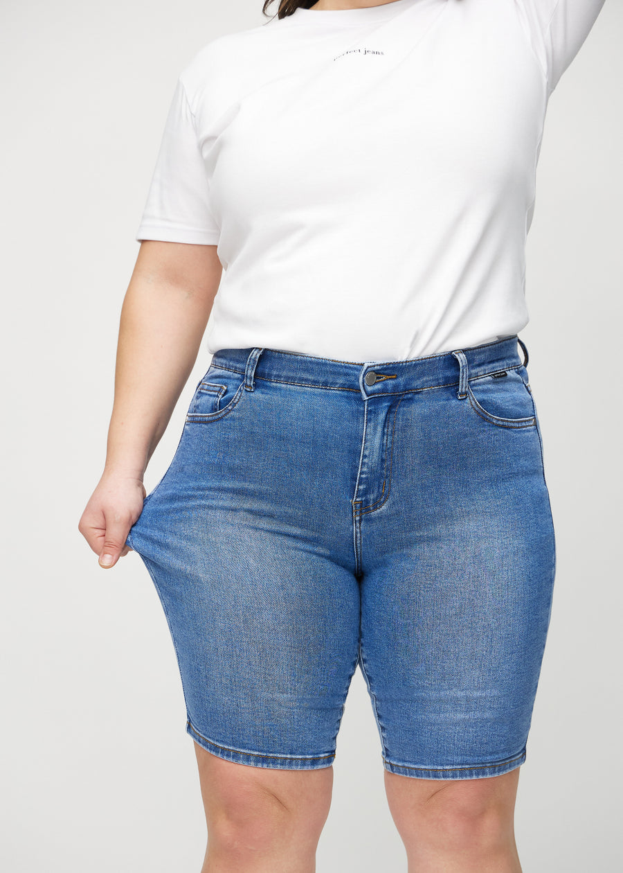 Plus-size-modellen strekker shortsen ved låret for å vise stretch.