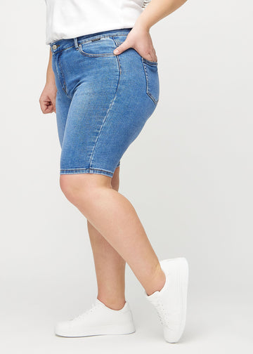 Denim skinny middle shorts sett fra siden på en plus-size-modell.