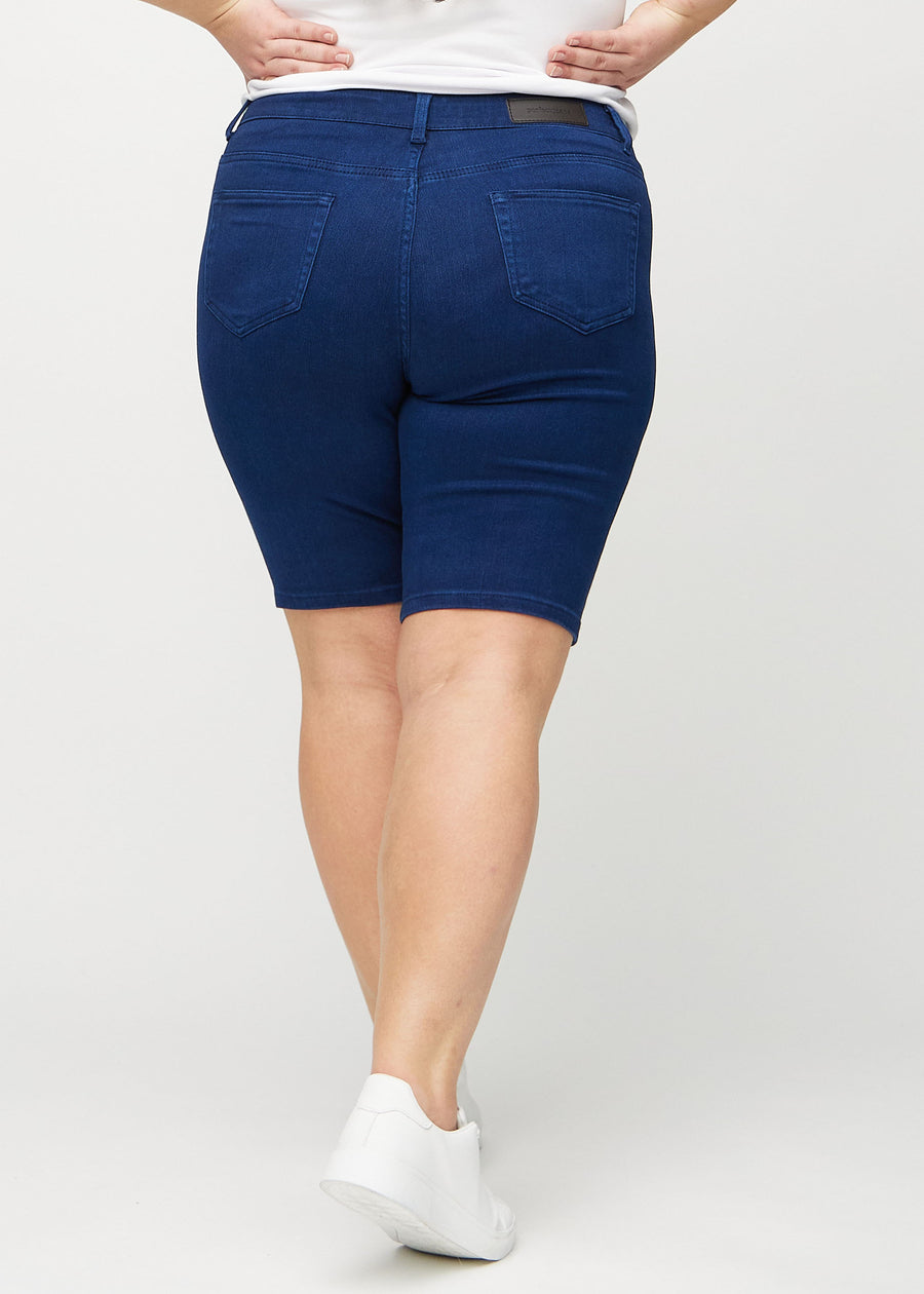 Mørkeblå skinny middle shorts sett bakfra på en plus-size-modell, så man kan se hele produktet.