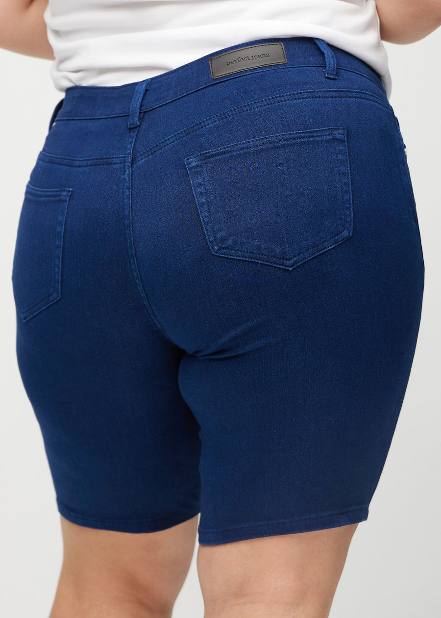 Mørkeblå skinny middle shorts sett bakfra på nært hold på en plus-size-modell for å vise detaljer.