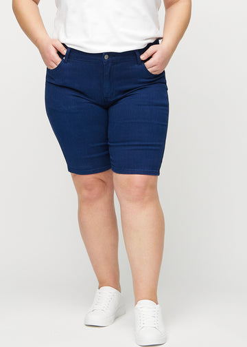Mørkeblå skinny middle shorts, modellnavn Royals, som sitter tett på låret og slutter rett over kneet på en plus-size-modell, sett forfra.
