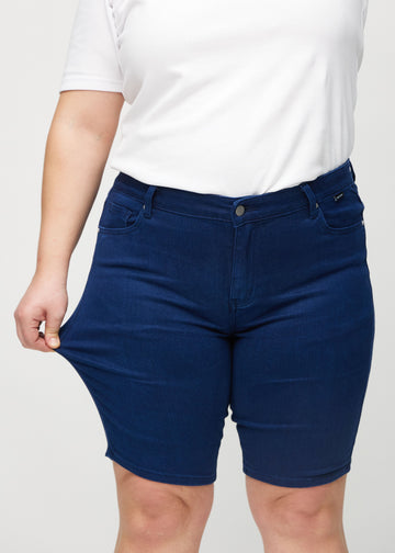 Plus-size-modellen strekker shortsen ved låret for å vise stretch.
