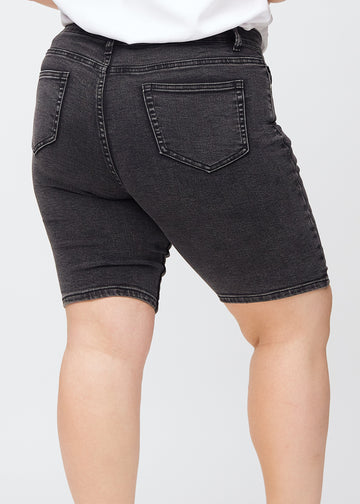 Mørkegrå denim skinny middle shorts sett bakfra tett på en plus-size modell for å vise detaljer.
